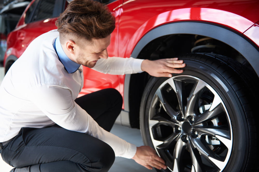salesman-checking-shiny-rims-new-car